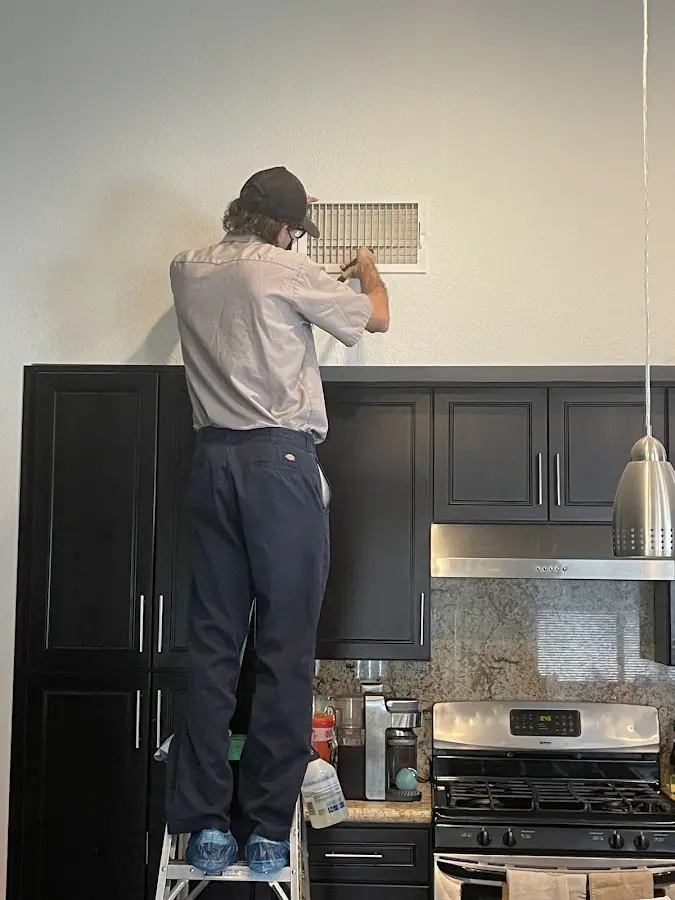 Technician inspecting an air vent during HVAC service in Miami